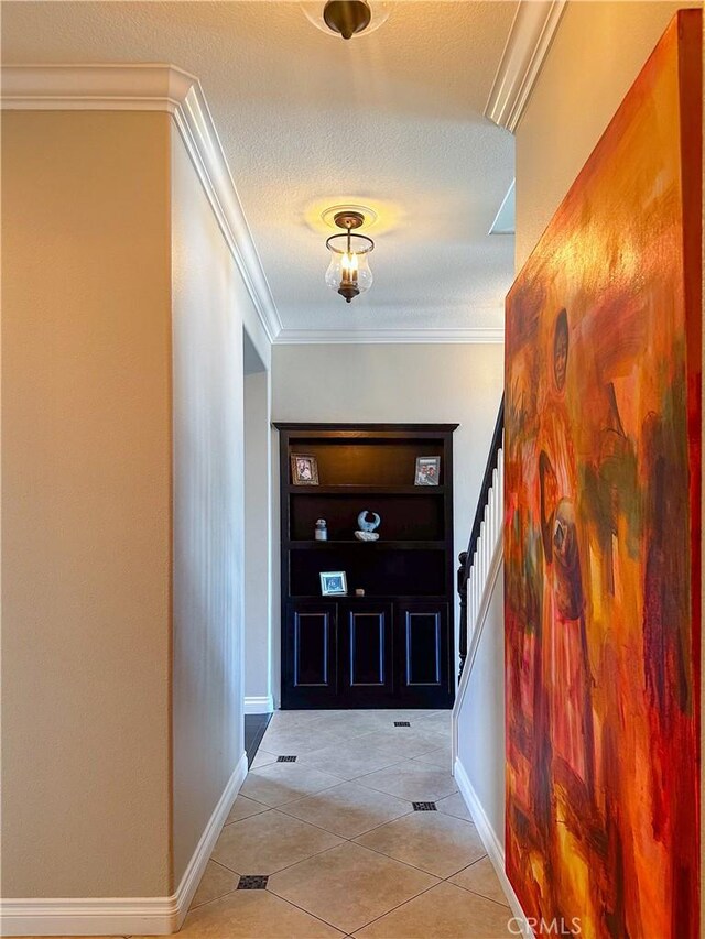 doorway to outside with light tile patterned floors, crown molding, and a textured ceiling