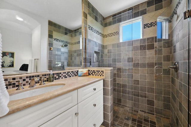 bathroom with vanity, backsplash, and a shower with shower door