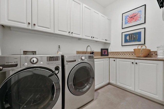 washroom with cabinets, light tile patterned flooring, and washer and clothes dryer