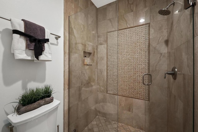 bathroom featuring toilet and a shower with shower door