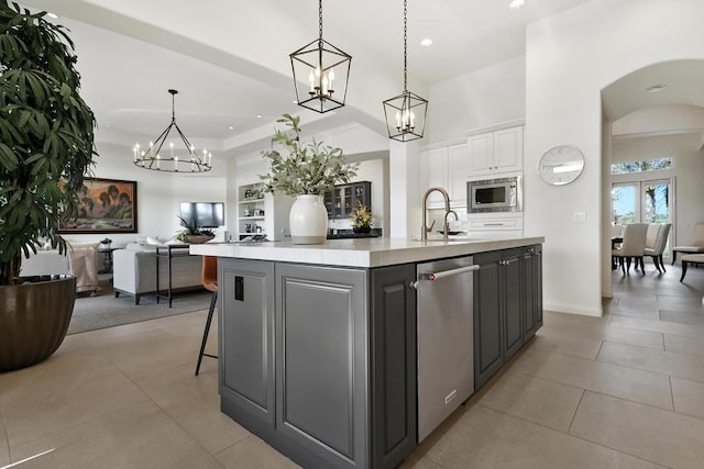 kitchen with pendant lighting, stainless steel appliances, a large island with sink, and white cabinets