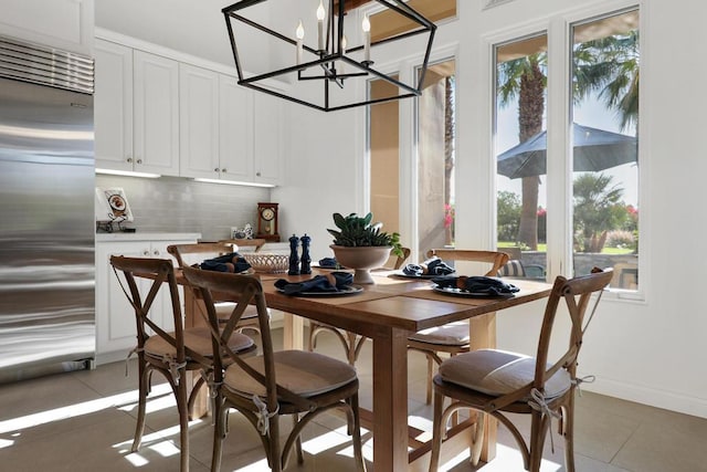 dining area featuring dark tile patterned flooring, a notable chandelier, and a healthy amount of sunlight