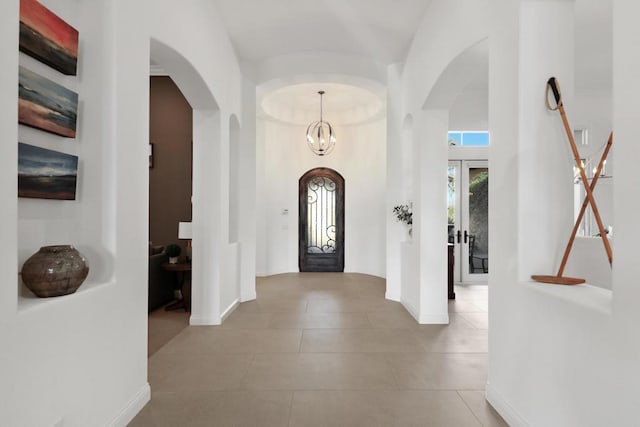 foyer entrance with a towering ceiling, an inviting chandelier, and french doors