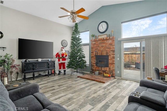 living room featuring light wood-type flooring, ceiling fan, a wood stove, and high vaulted ceiling