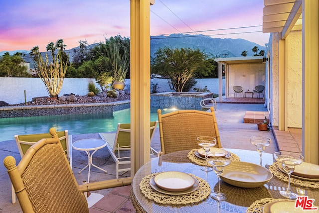 exterior space with an outdoor hot tub, a patio area, and a mountain view