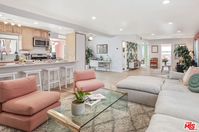 living room with sink, a chandelier, and light hardwood / wood-style floors