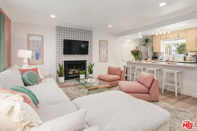 living room with sink, light hardwood / wood-style flooring, and a tiled fireplace