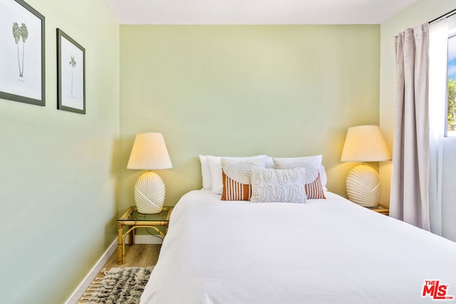 bedroom with multiple windows and hardwood / wood-style floors