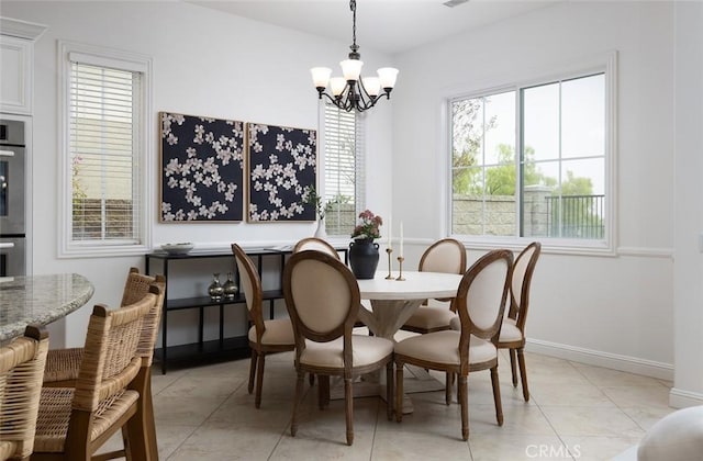 dining space with light tile patterned floors, plenty of natural light, and a chandelier