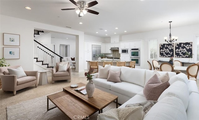 living room featuring ceiling fan with notable chandelier and sink