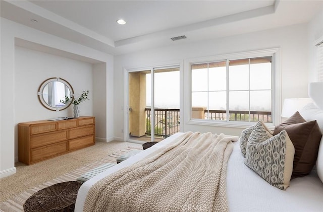 carpeted bedroom with access to exterior and a tray ceiling