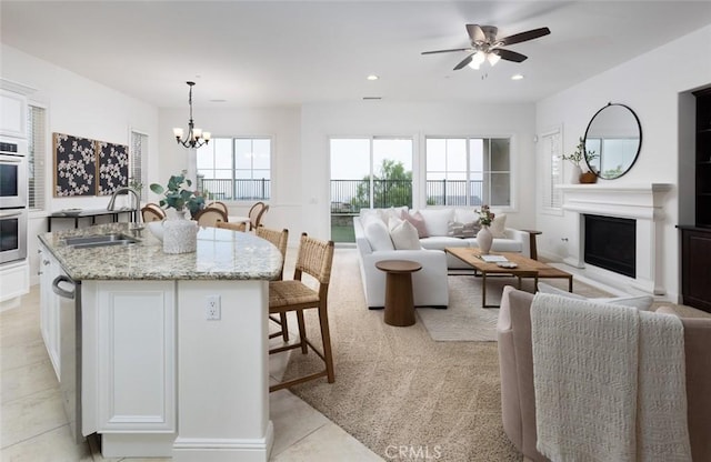 kitchen featuring white cabinetry, a breakfast bar area, decorative light fixtures, light stone countertops, and sink