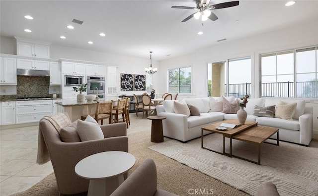 tiled living room featuring ceiling fan with notable chandelier