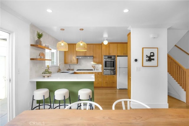 kitchen featuring decorative light fixtures, white refrigerator, decorative backsplash, sink, and kitchen peninsula