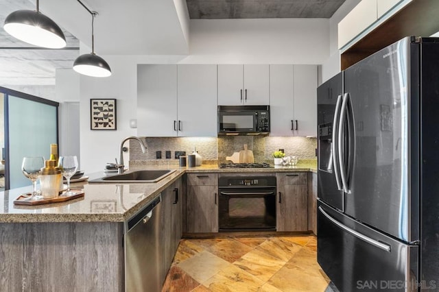 kitchen with black appliances, backsplash, pendant lighting, light stone counters, and sink