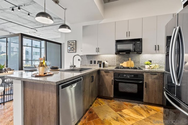 kitchen featuring decorative light fixtures, sink, backsplash, and black appliances