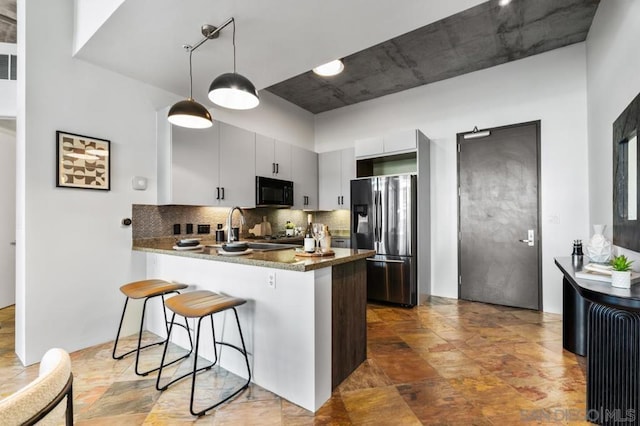 kitchen featuring decorative light fixtures, kitchen peninsula, decorative backsplash, sink, and stainless steel fridge with ice dispenser