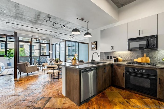 kitchen featuring white cabinetry, kitchen peninsula, black appliances, pendant lighting, and sink