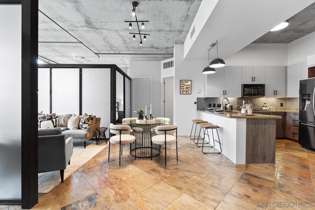 kitchen featuring kitchen peninsula, a breakfast bar area, backsplash, black appliances, and sink