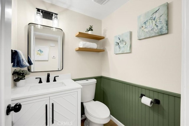 bathroom with toilet, vanity, and wooden walls