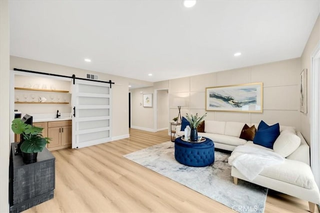 living room featuring light wood-type flooring, a barn door, and sink