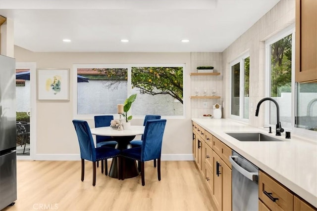 kitchen featuring backsplash, sink, light wood-type flooring, appliances with stainless steel finishes, and light brown cabinets