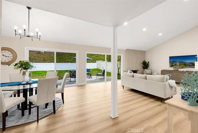 living room with light hardwood / wood-style floors, plenty of natural light, a chandelier, and vaulted ceiling