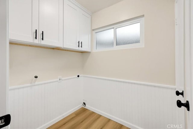 clothes washing area with cabinets and light hardwood / wood-style flooring