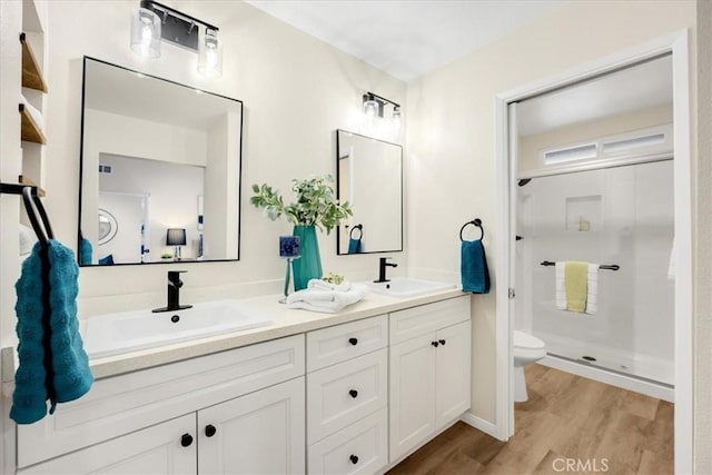 bathroom featuring toilet, vanity, a shower with door, and hardwood / wood-style floors