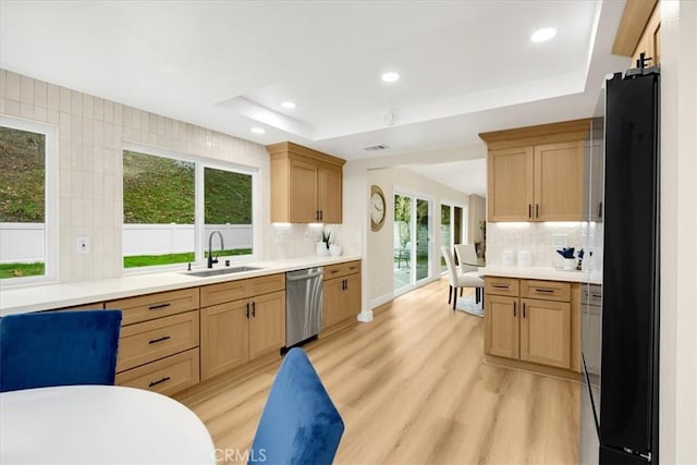 kitchen featuring decorative backsplash, sink, black fridge, a raised ceiling, and stainless steel dishwasher