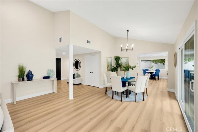 dining space with an inviting chandelier, light hardwood / wood-style floors, and high vaulted ceiling