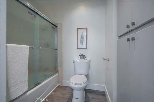 bathroom featuring toilet, enclosed tub / shower combo, and hardwood / wood-style floors