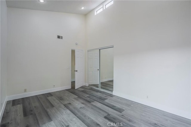 spare room featuring a towering ceiling and hardwood / wood-style flooring