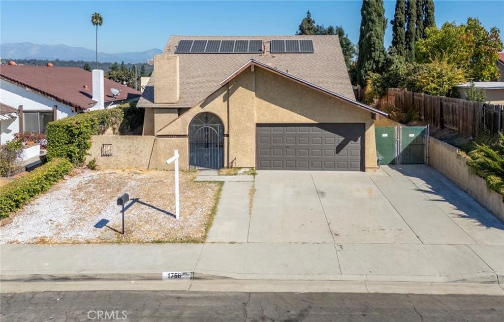 view of front facade with a mountain view, solar panels, and a garage