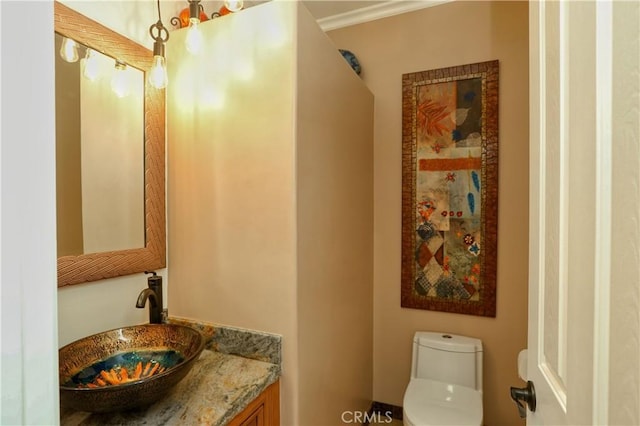 bathroom featuring toilet, vanity, and ornamental molding