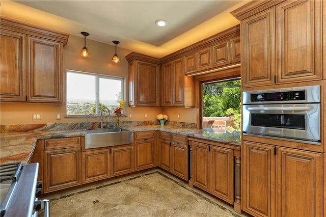 kitchen with sink, stainless steel appliances, a wealth of natural light, and decorative light fixtures