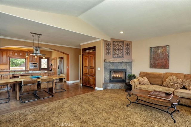 living room with lofted ceiling, a premium fireplace, dark hardwood / wood-style floors, ceiling fan, and crown molding