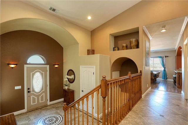 entrance foyer featuring ornamental molding and vaulted ceiling