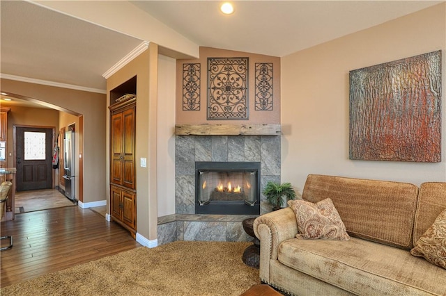 living room featuring vaulted ceiling, a tile fireplace, dark hardwood / wood-style flooring, and crown molding