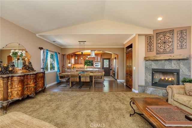 dining space featuring crown molding, a tile fireplace, lofted ceiling, and dark colored carpet