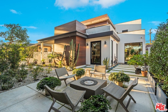 rear view of property with an outdoor fire pit and a patio