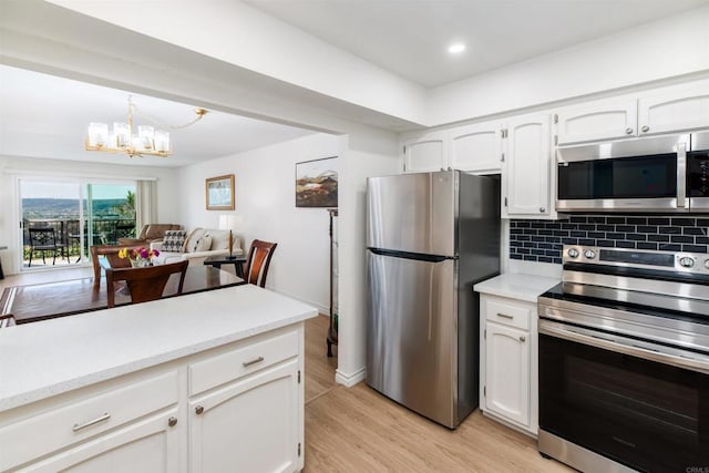 kitchen with an inviting chandelier, appliances with stainless steel finishes, decorative backsplash, hanging light fixtures, and white cabinets