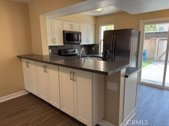 kitchen with kitchen peninsula, stainless steel appliances, and white cabinetry