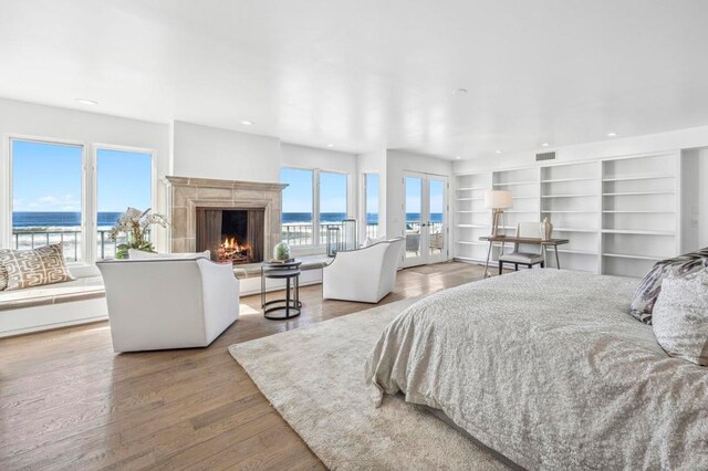 bedroom with wood-type flooring, french doors, access to outside, and a water view