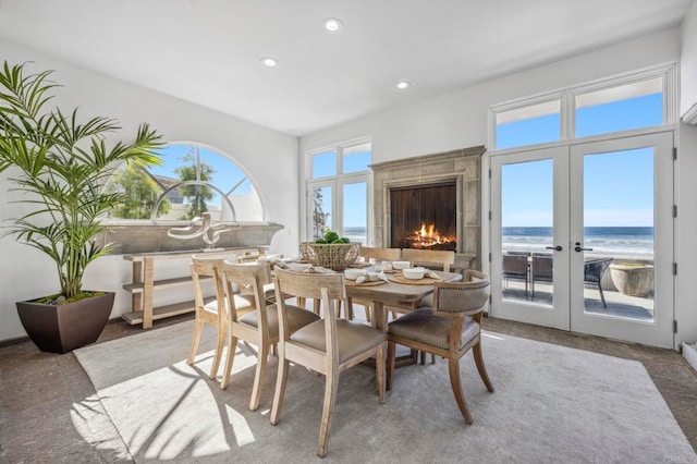 dining room with a beach view, a water view, and french doors