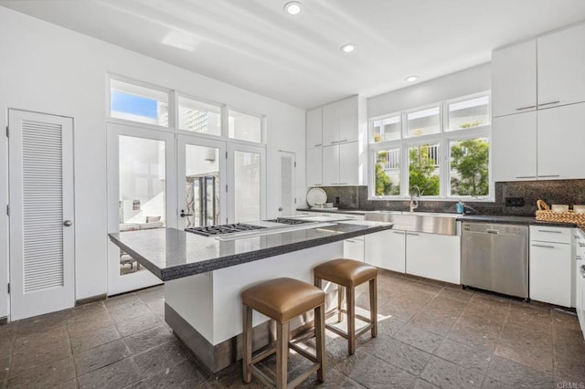 kitchen with white cabinetry, stainless steel dishwasher, a center island, and a breakfast bar area