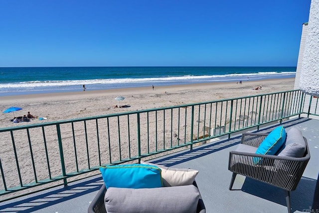 balcony featuring a water view and a beach view