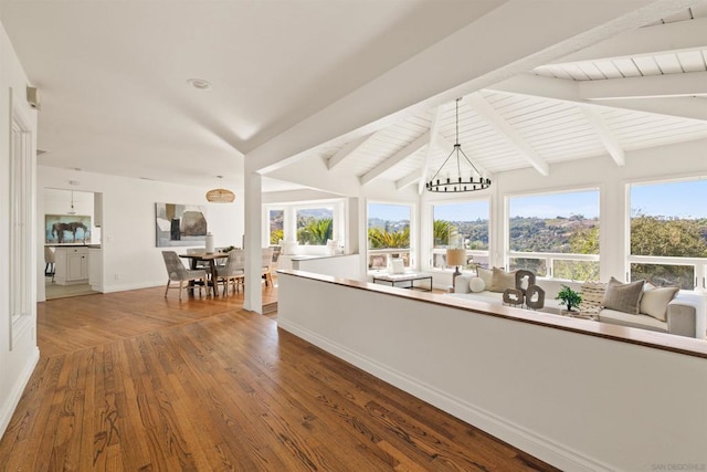 interior space featuring vaulted ceiling with beams, an inviting chandelier, and hardwood / wood-style flooring