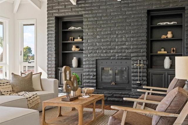 sitting room with a brick fireplace, hardwood / wood-style flooring, built in features, and beam ceiling