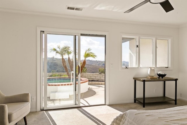 bedroom with light carpet, ceiling fan, access to exterior, a mountain view, and crown molding